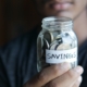 a man holding a jar with a savings label on it