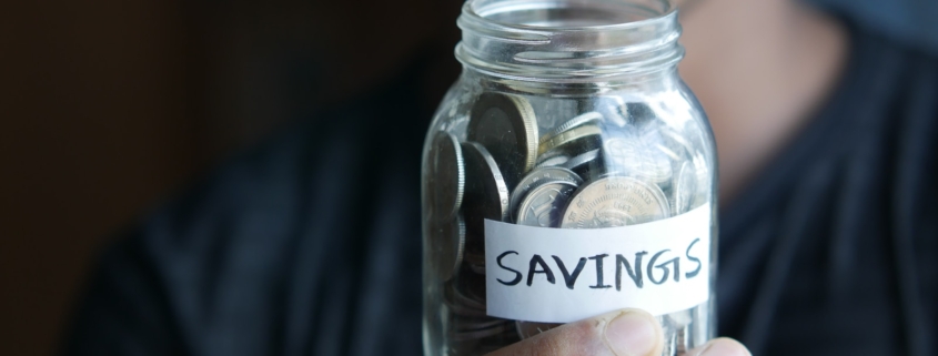 a man holding a jar with a savings label on it