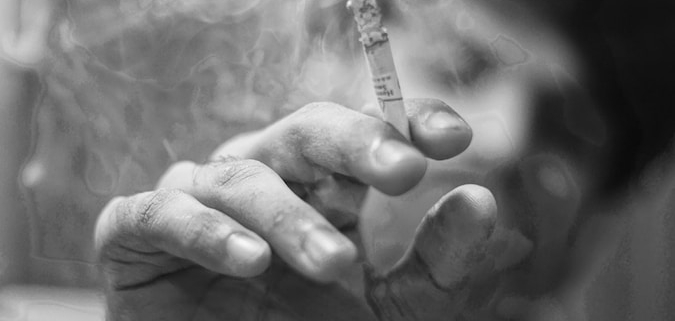 grayscale photo of person holding cigarette stick