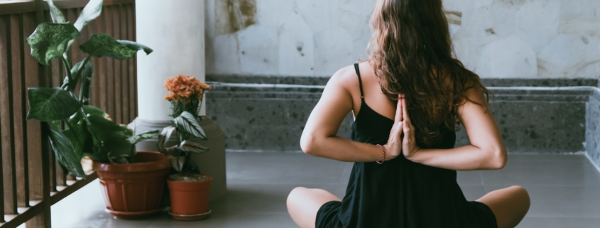 woman wearing black shirt sitting on green yoga mat