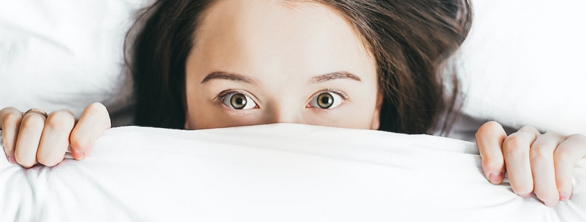 woman covering her face with blanket