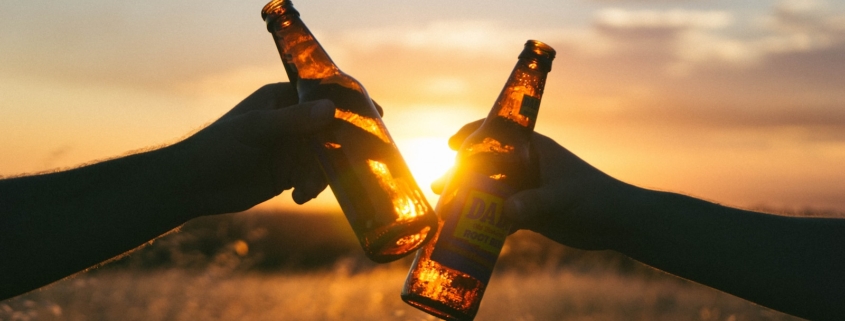 photography of person holding glass bottles during sunset