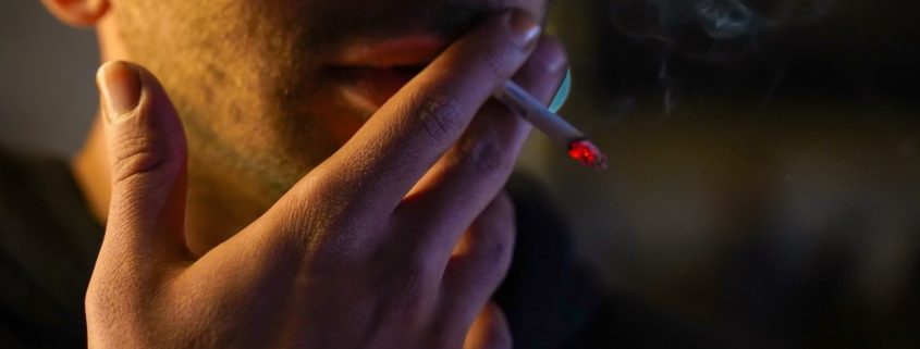 a man smoking a cigarette in the dark