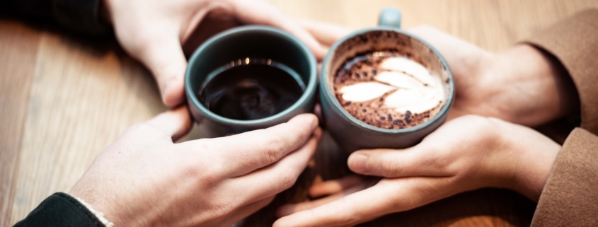 two person holding ceramic mugs with coffee