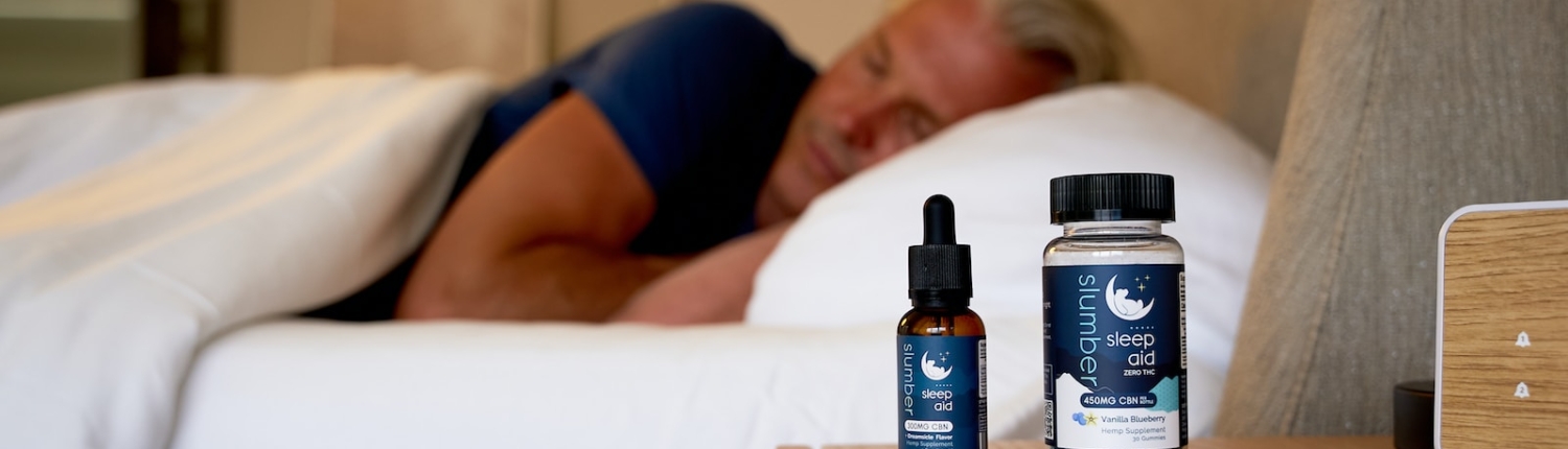 a man sleeping on a bed next to a bottle of cb