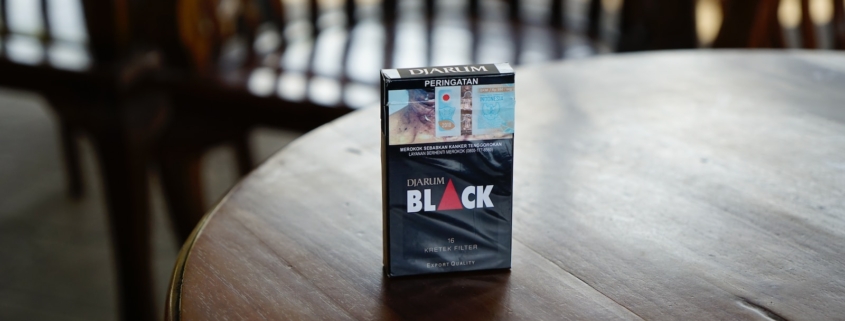 Black cigarette box on top of brown wooden table